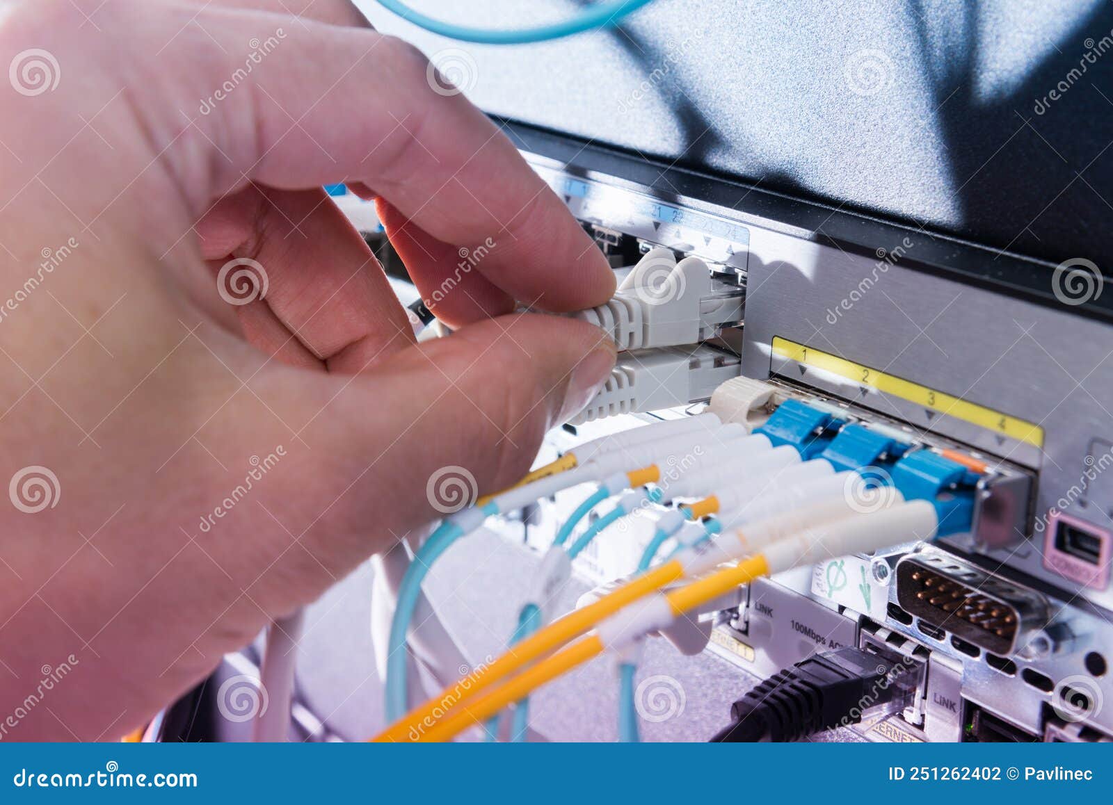 Hand of Computer Engineer Connecting Fiber Optic Cable in Server Stock