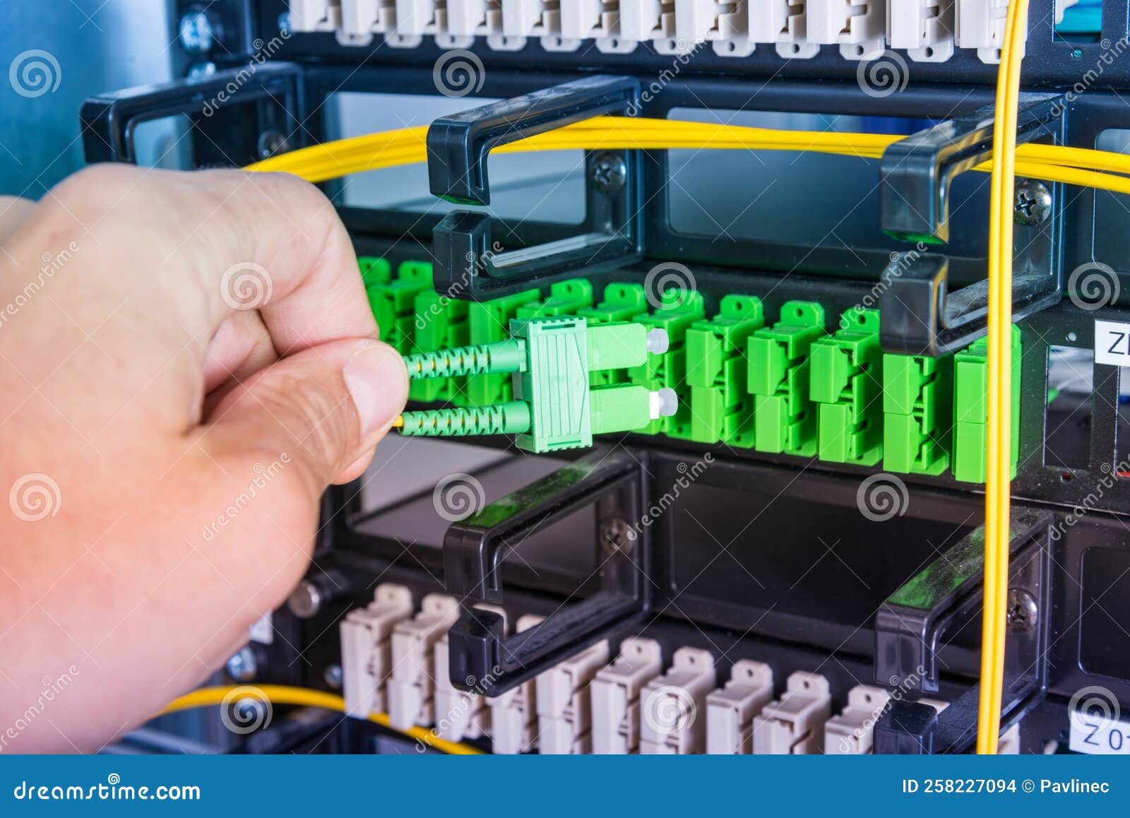 Hand of Computer Engineer Connecting Fiber Optic Cable in Server Stock