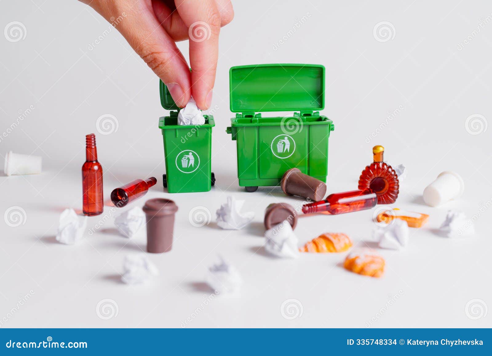 hand disposing wrapping paper into miniature green trash bins