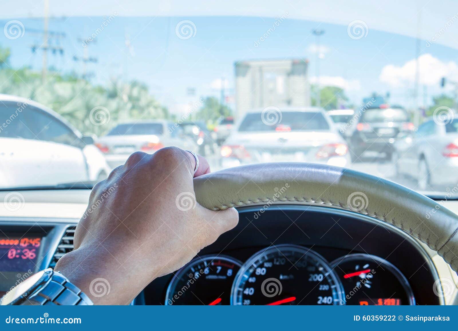 Hand of Driver Holding Steering Wheel, with Traffic View in the City