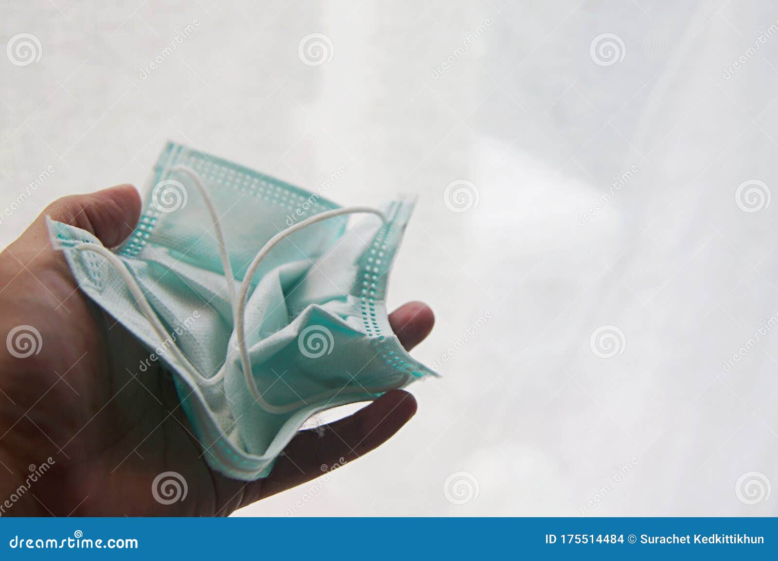 hand hold folded face mask sheet before throw away littering - safety way to disposal used mask sheet