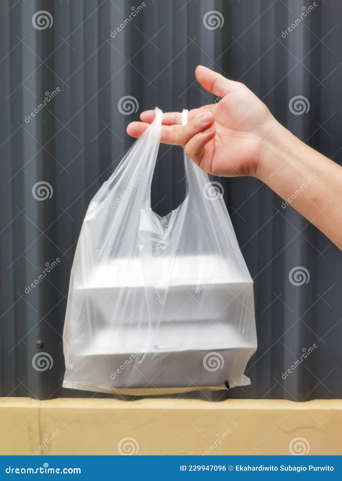 hand holding a bag of take away food in polystyrene container.