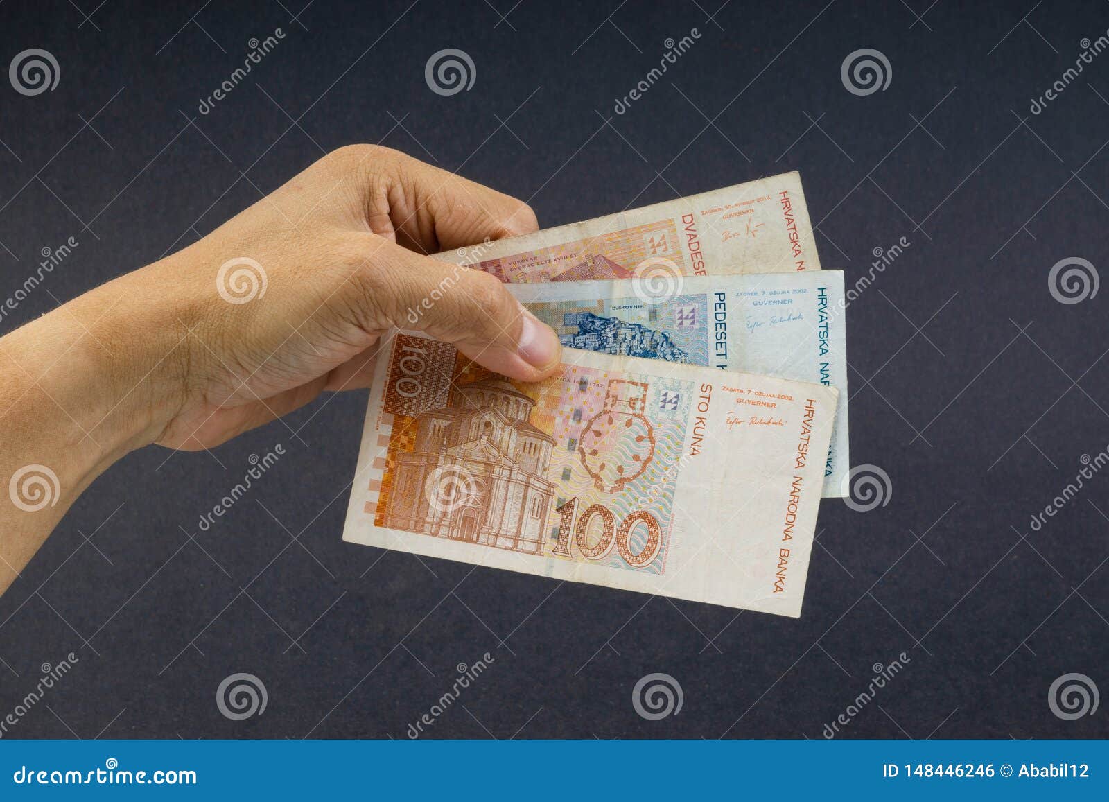 hand holding croatian kuna or sto kuna bank notes on black background.