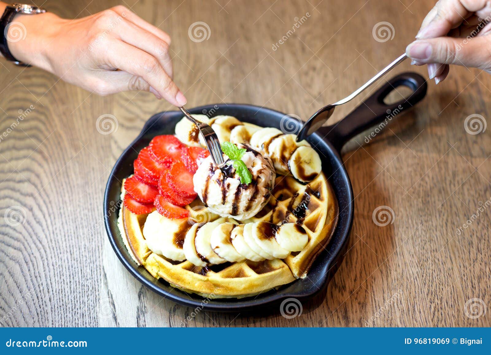 Hand Holding Fork Eating Waffle with Vanilla Ice Cream and Fresh Stock