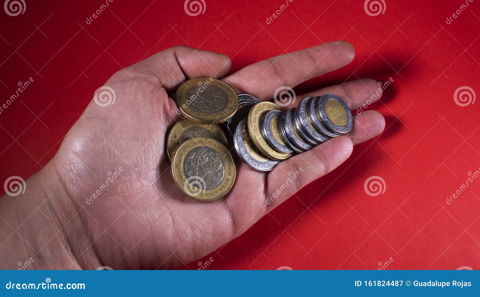 hand holding a handful of mexican pesos on a red background