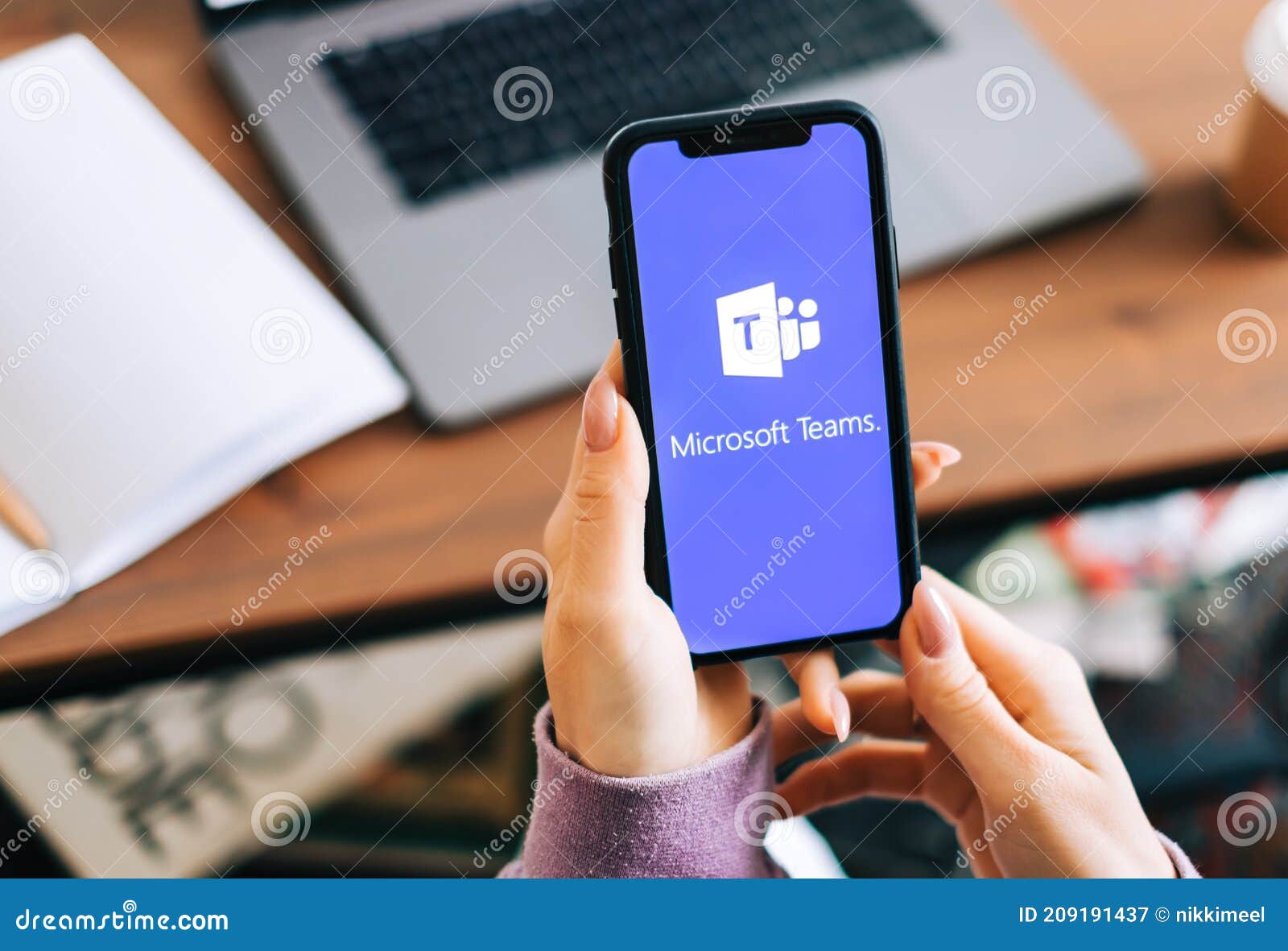 Hand Holding IPhone with Microsoft Teams Video Call App Logo on the