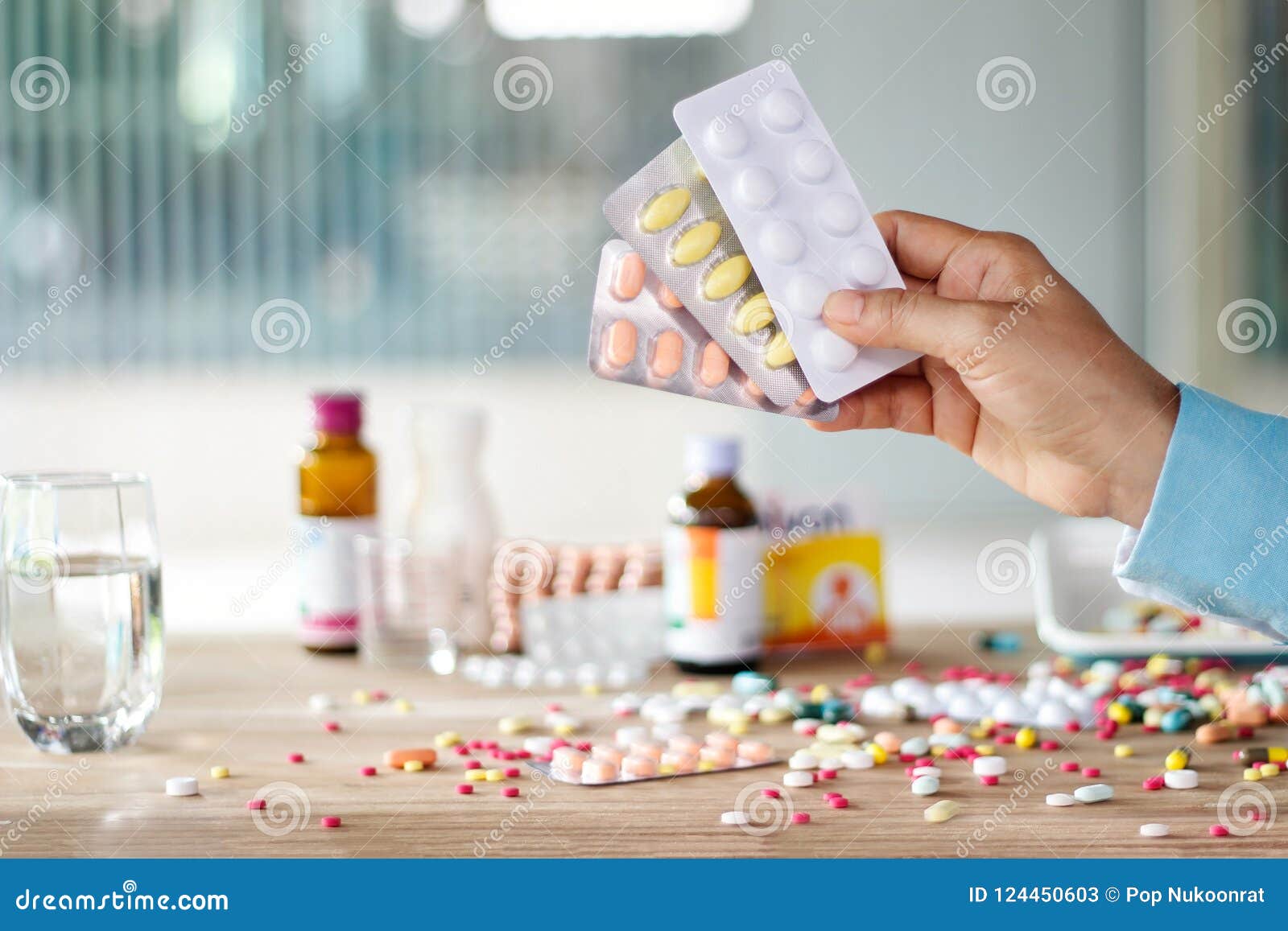 hand holding medicines pill pack with colorful drugs spread on