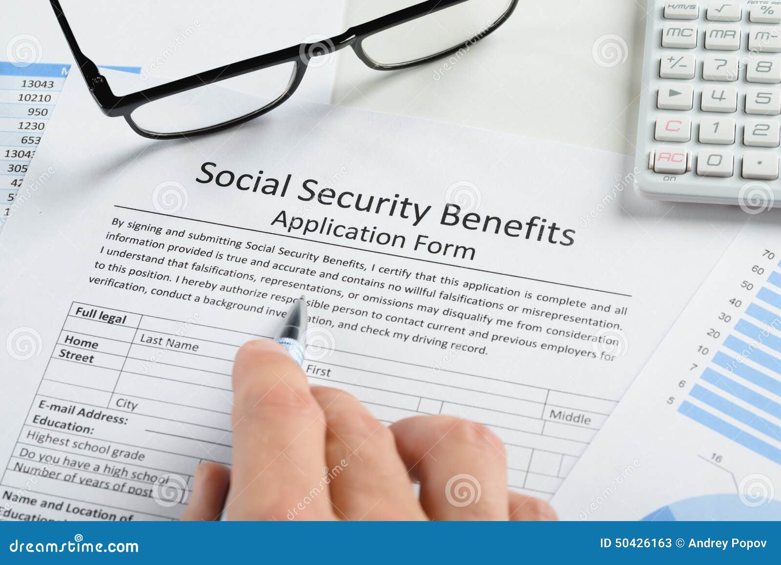 hand holding pen over social security benefits form