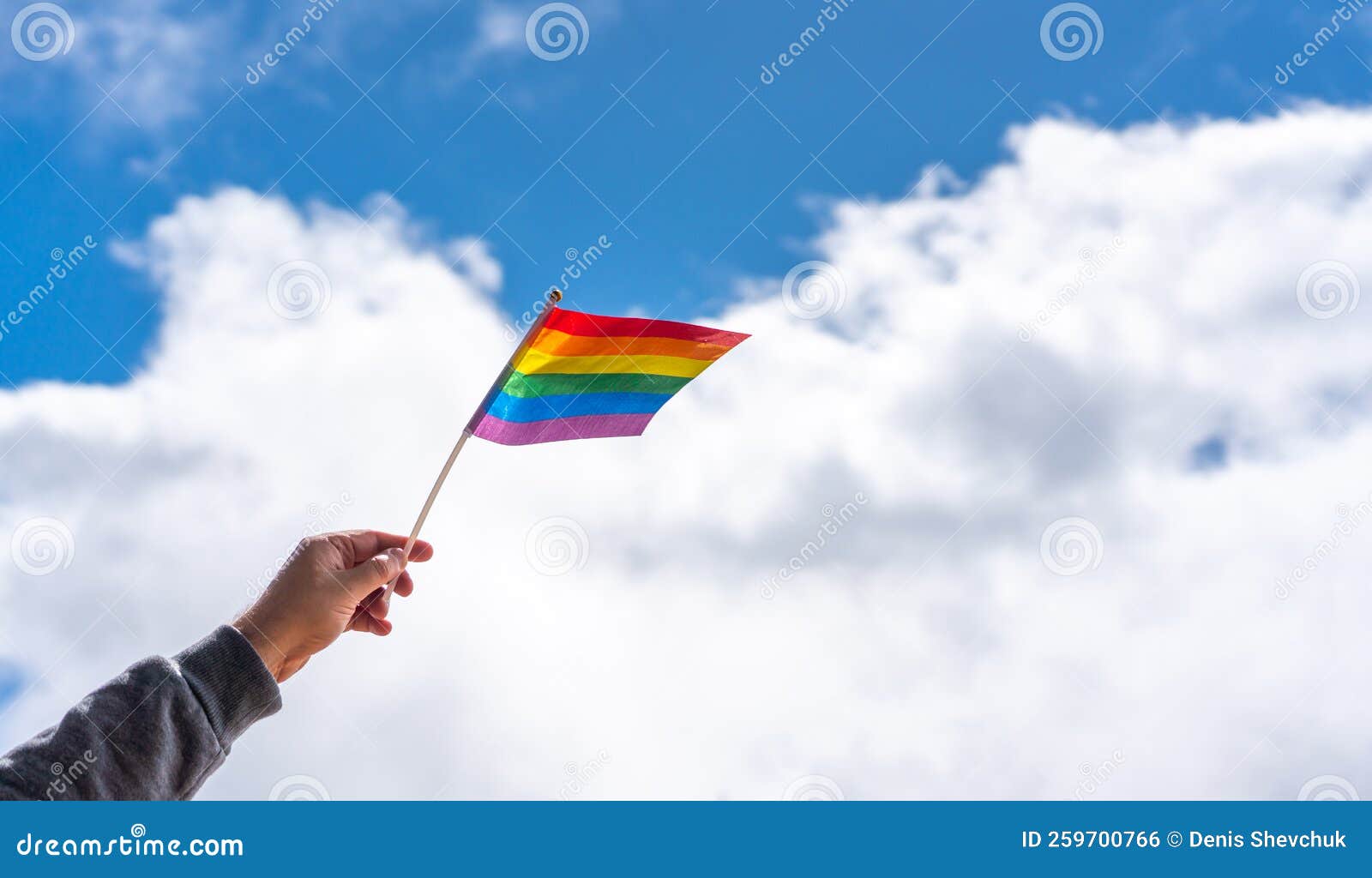 The Hand Holds in the Fingers in the Wind the LGBT Flag on a Cloudy