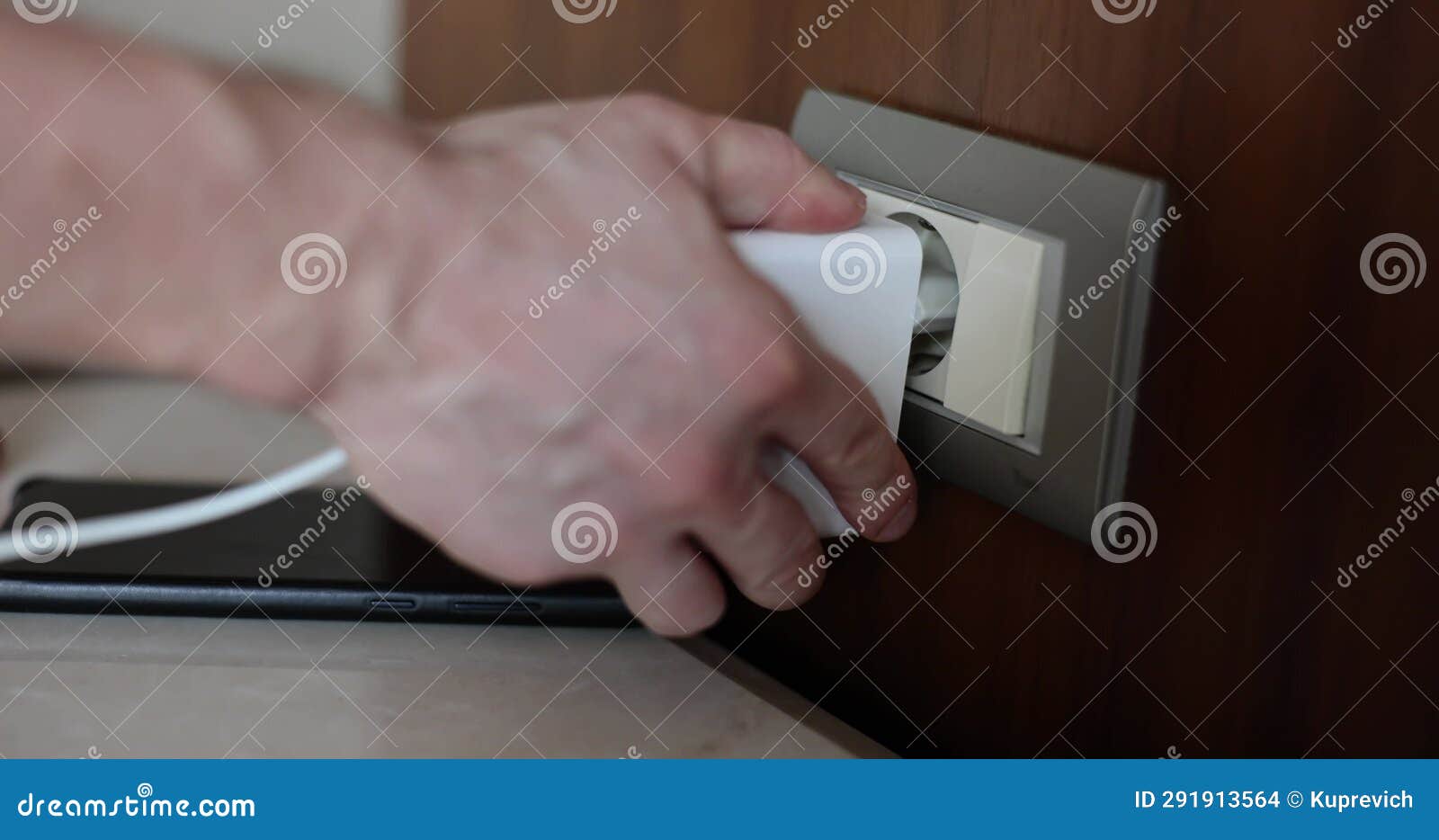 Hand Inserts Plug into Electrical Outlet Charges Phone from Usb Device