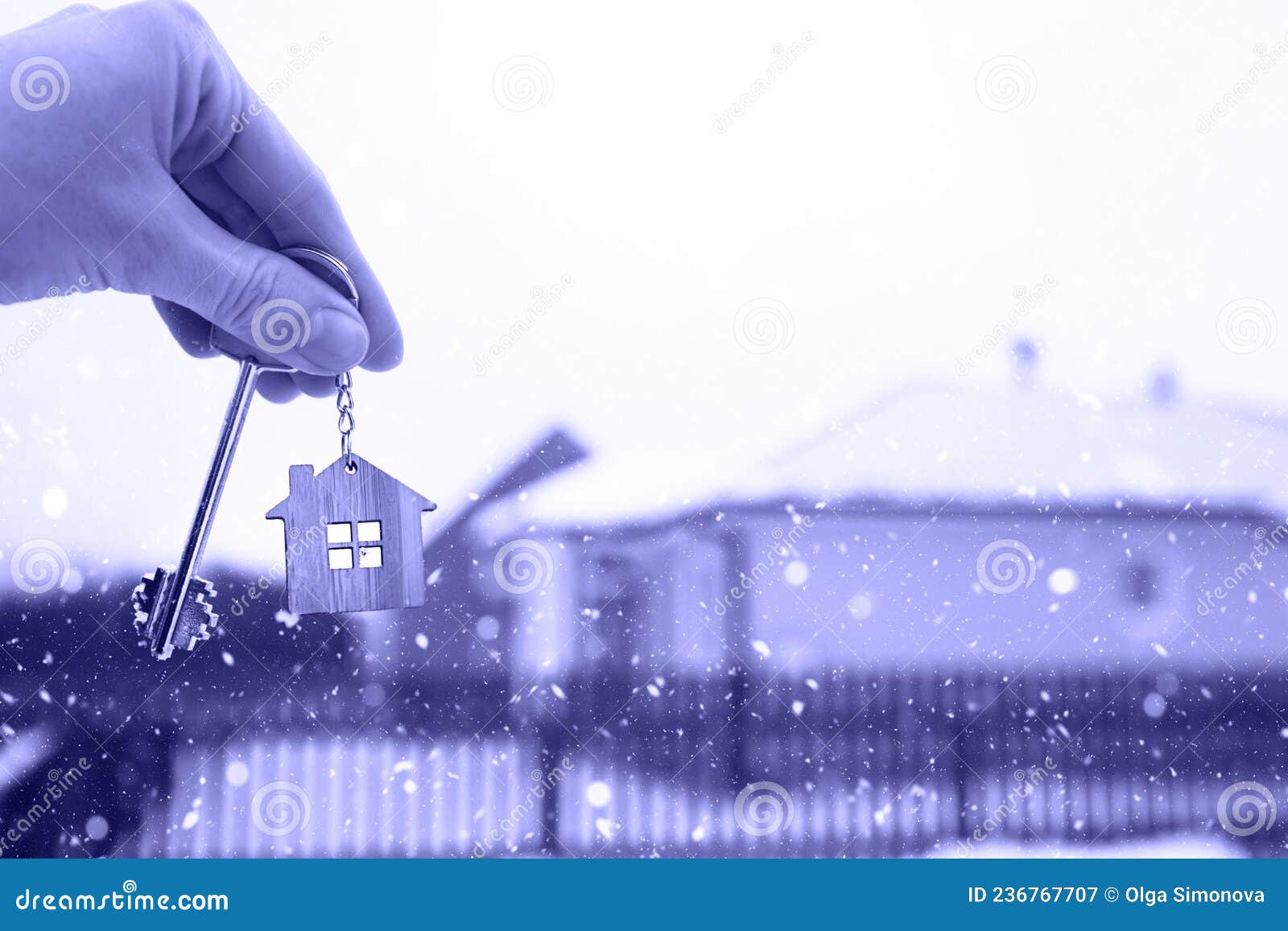 hand with a key of the house in winter in the snow. background of fence and cottage. give a gift for new year, christmas. moving