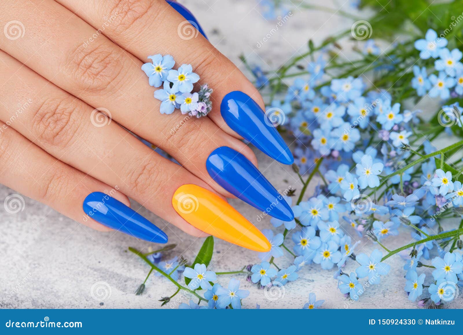 hand with long artificial manicured nails colored with blue and orange nail polish