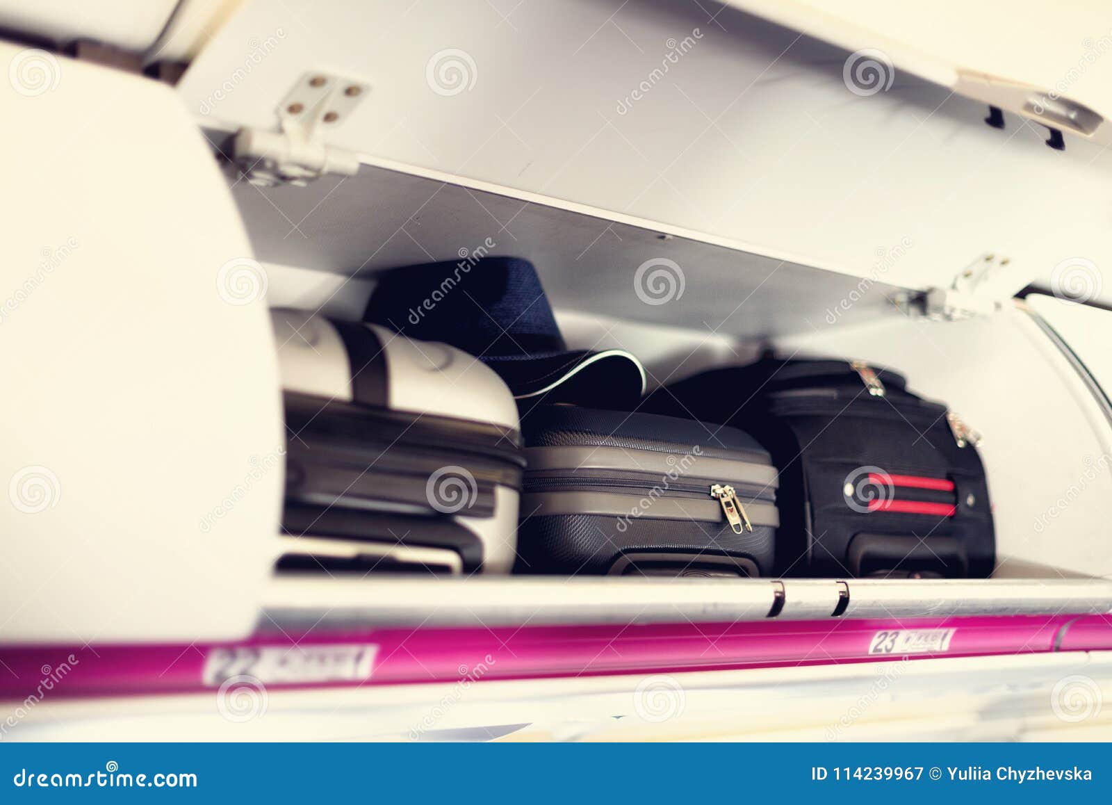 hand-luggage compartment with suitcases in airplane. carry-on luggage on top shelf of plane. travel concept with copy