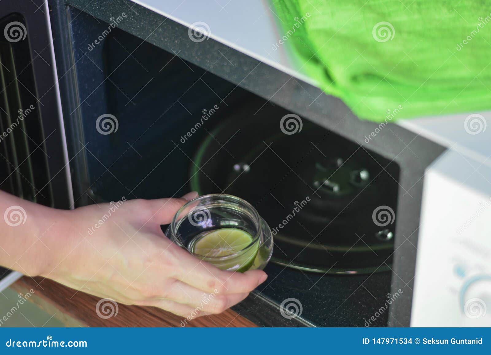 Hand with Microfiber Cleaning Rag Wiping Inside of Microwave Oven