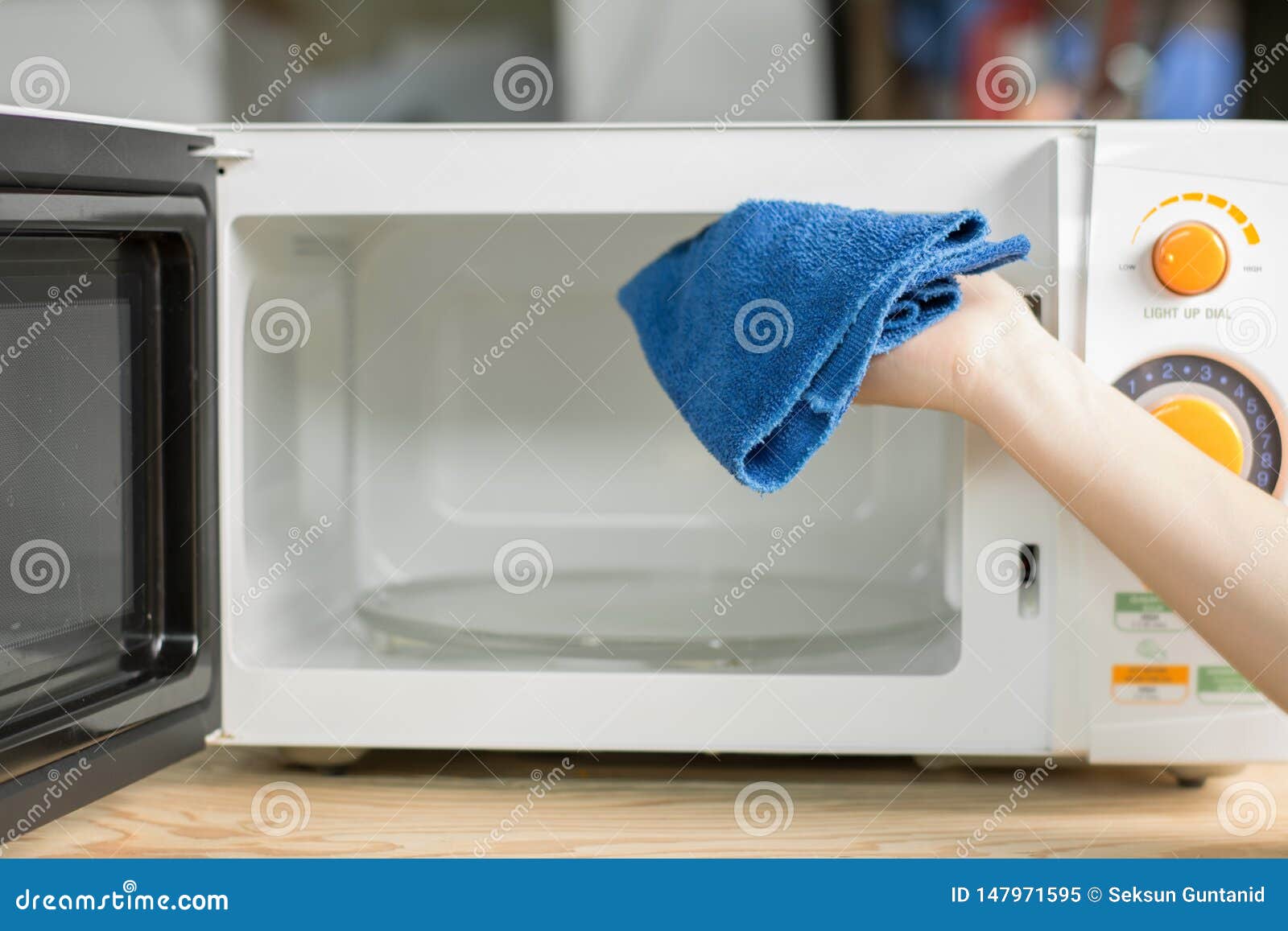 Hand With Microfiber Cleaning Rag Wiping Inside Of Microwave