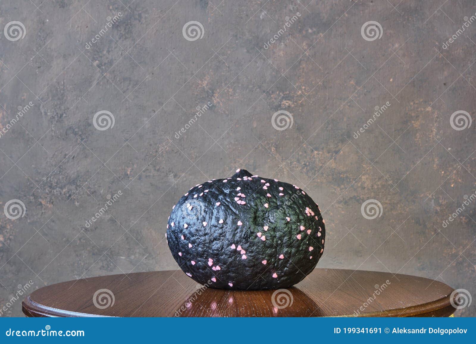 black coloured pumpkin with glitter on wooden stool in front of a brown backdrop