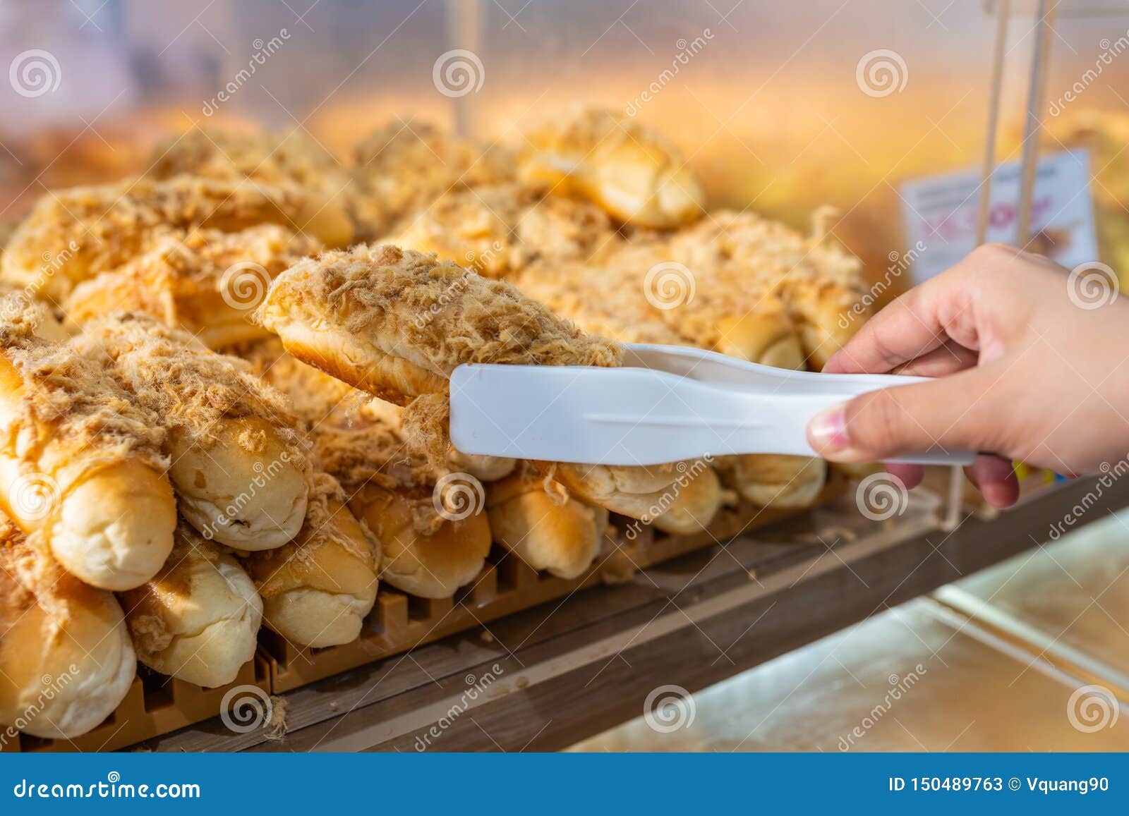 Close Up of Hand Picking Pork Floss Bread with Clamp Stock Image