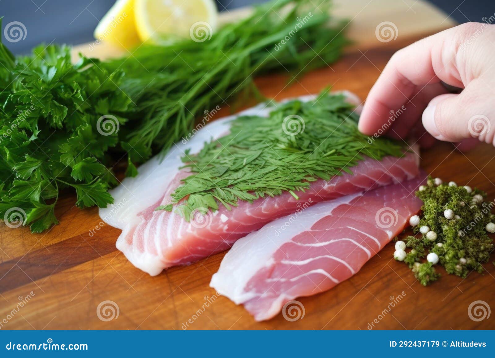 Hand Placing Fresh Herbs on Lightly Flaked Fish Steak Stock Image