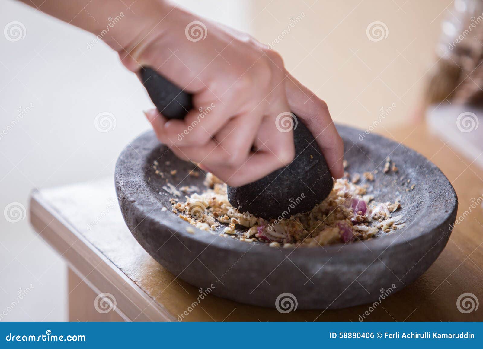 hand pounding herbs on a traditional pounder