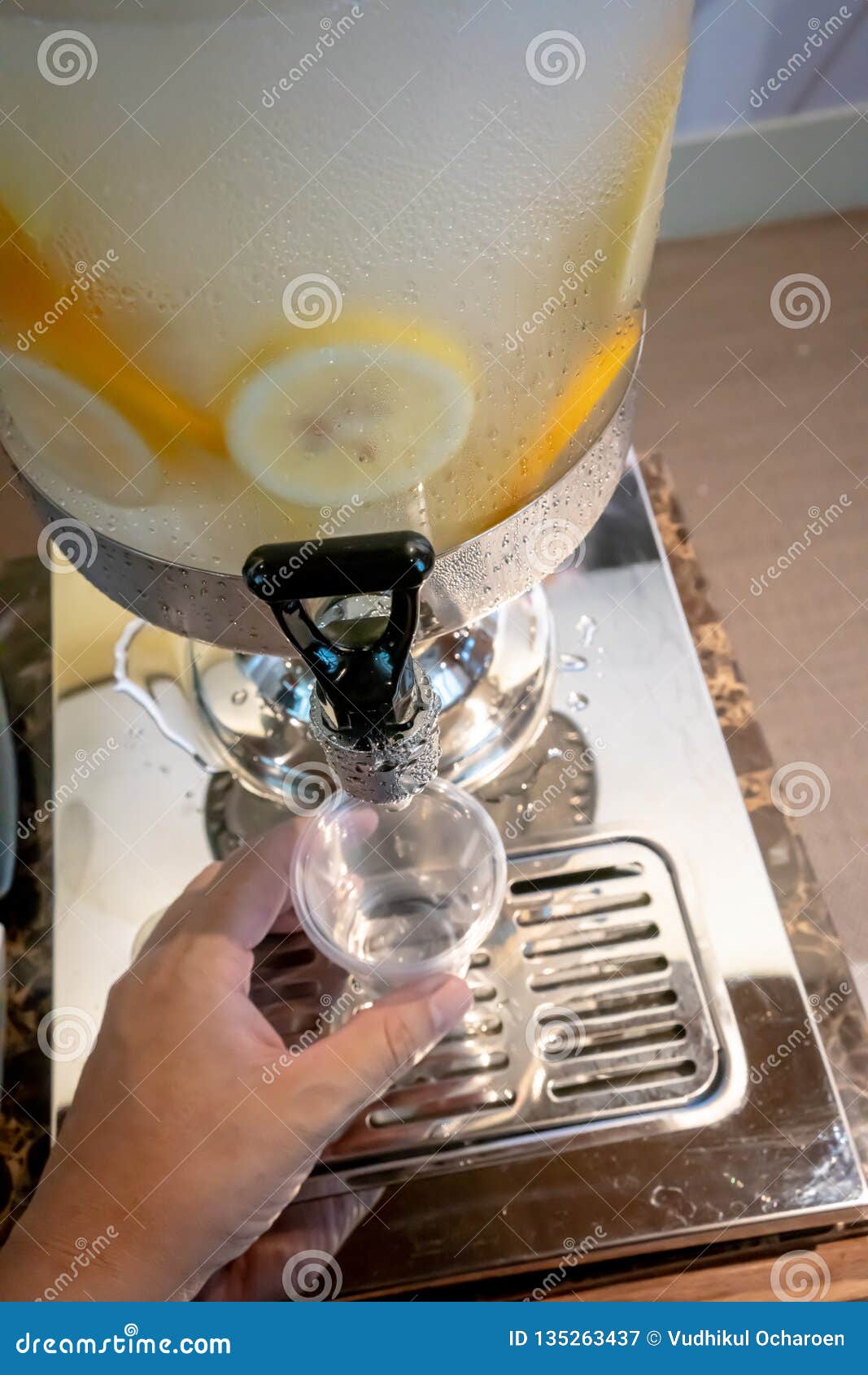 Hand Pulling Down the Lever of Water Dispenser with Fruit Infused Water