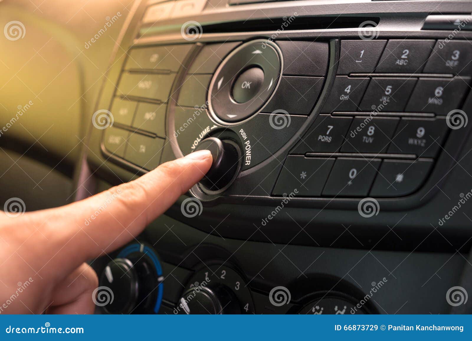 hand pushing the power button to turn on the car stereo