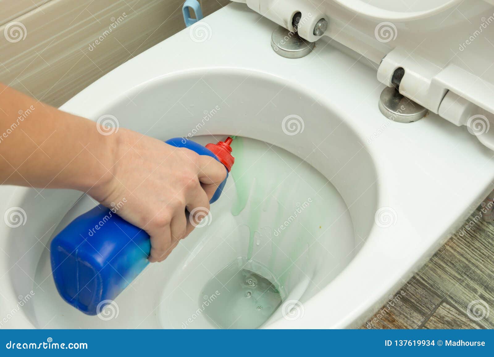 The Hand Puts a Liquid Detergent Under the Rim of the Toilet Bowl Stock