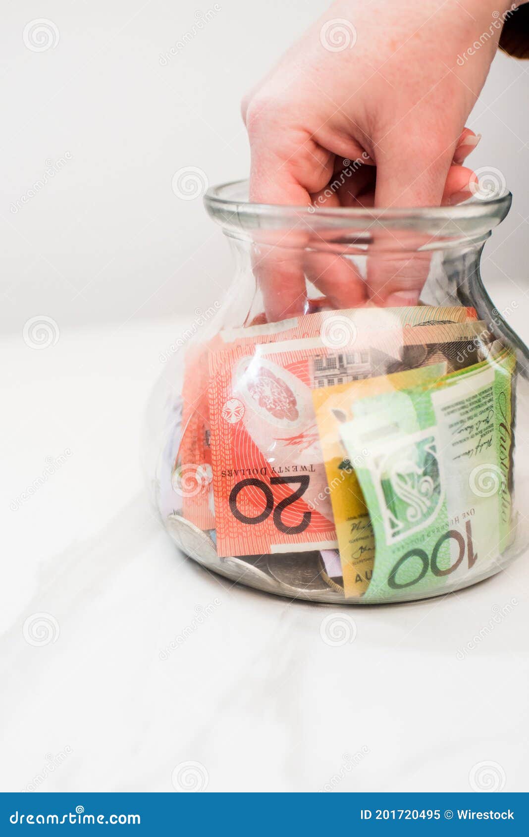 Hand Putting an Australian Dollar Banknote in a Transparent Jar on the White Background - of note, payment: 201720495