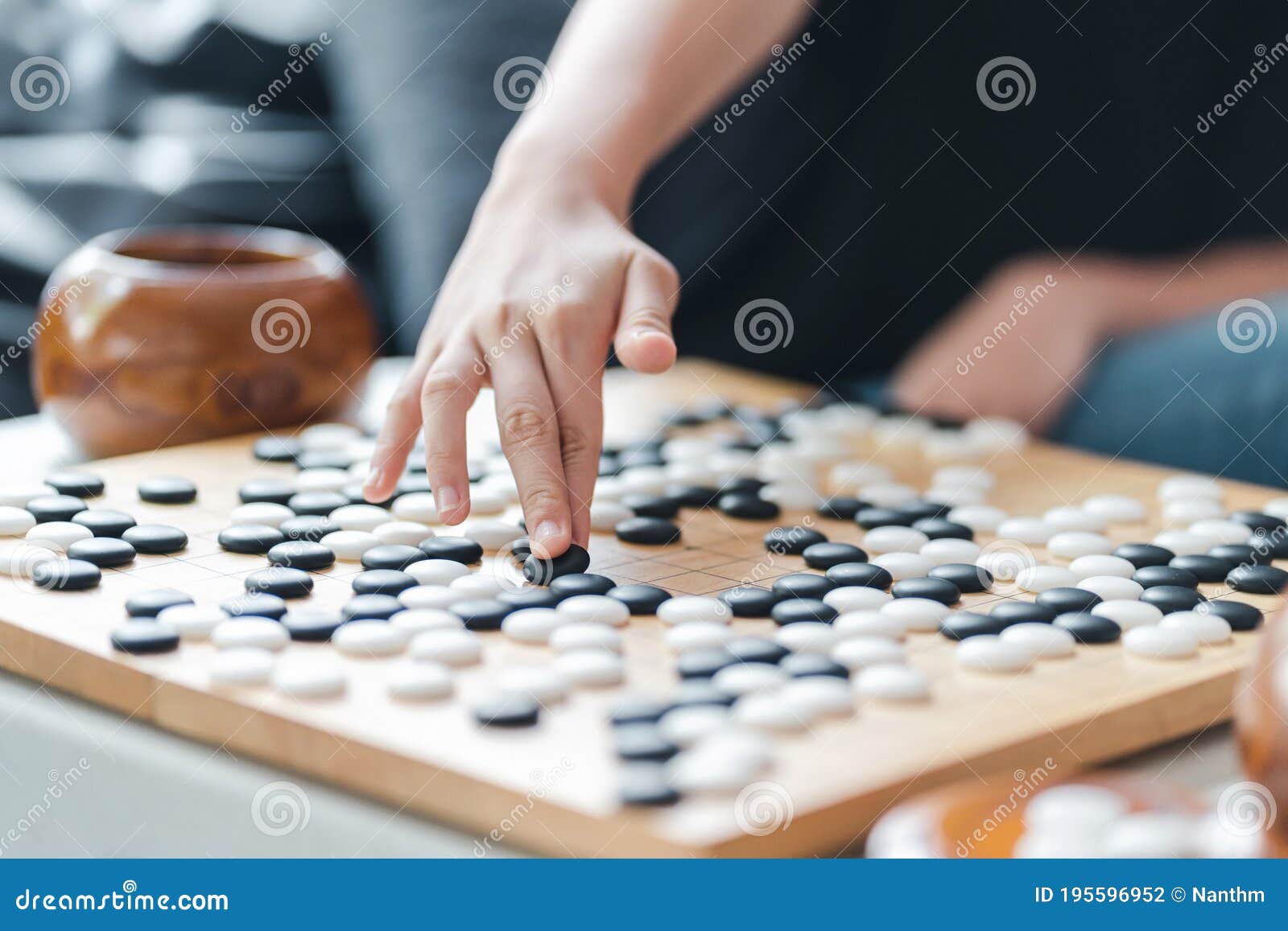 hand putting baduk blackstone on wooden grid board