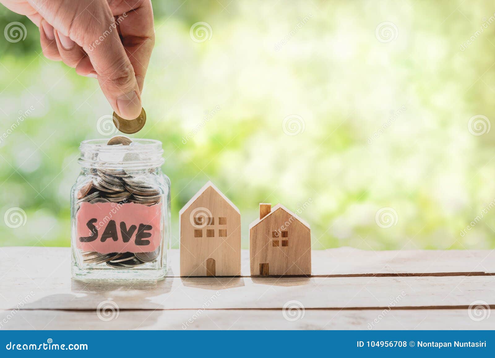 Hand Putting Coin In Glass Jar For Saving Money For Buying House