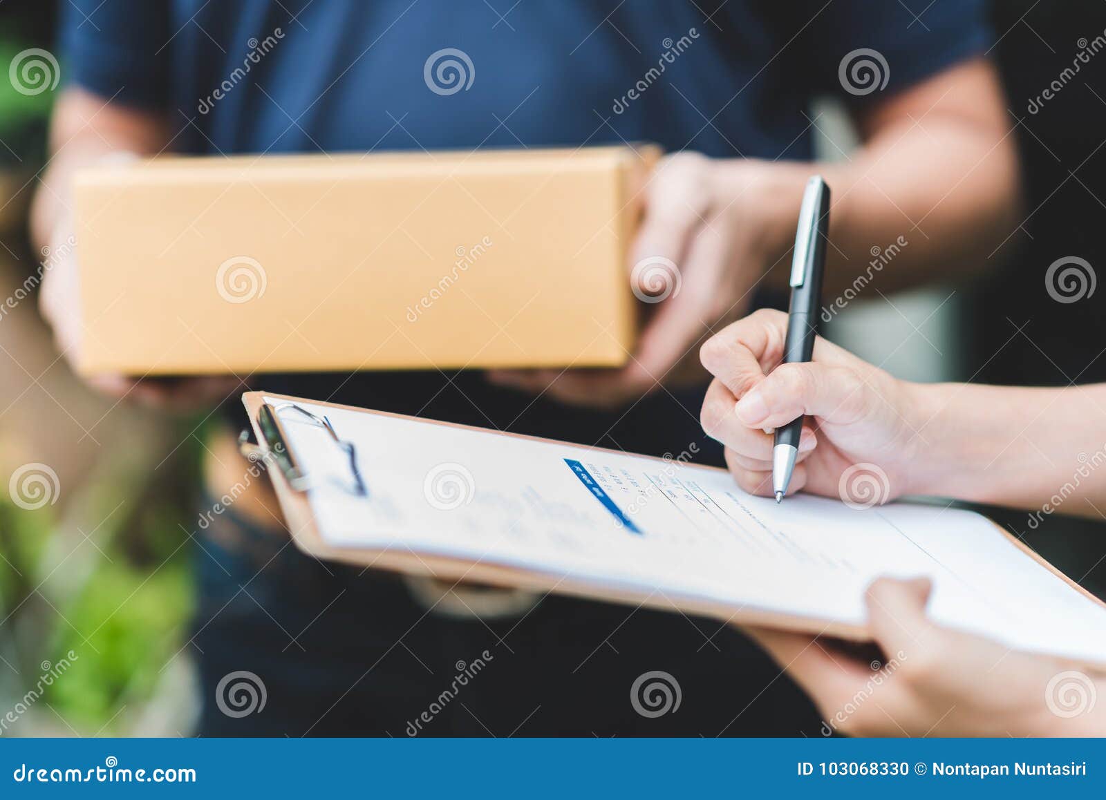 hand putting signature in clipboard to receive package from delivery man