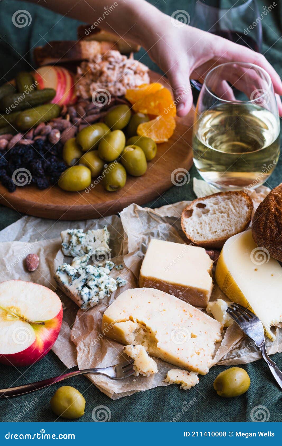 A Hand Reaching for White Wine in a Cheese Board Spread Stock Photo