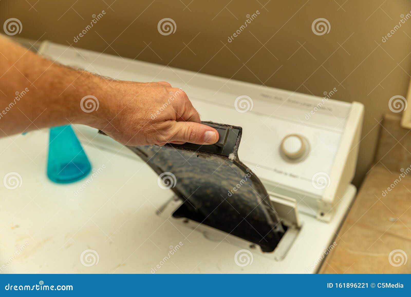 Hand Removing Dirty Lint Trap from Dryer while Doing Laundry Stock