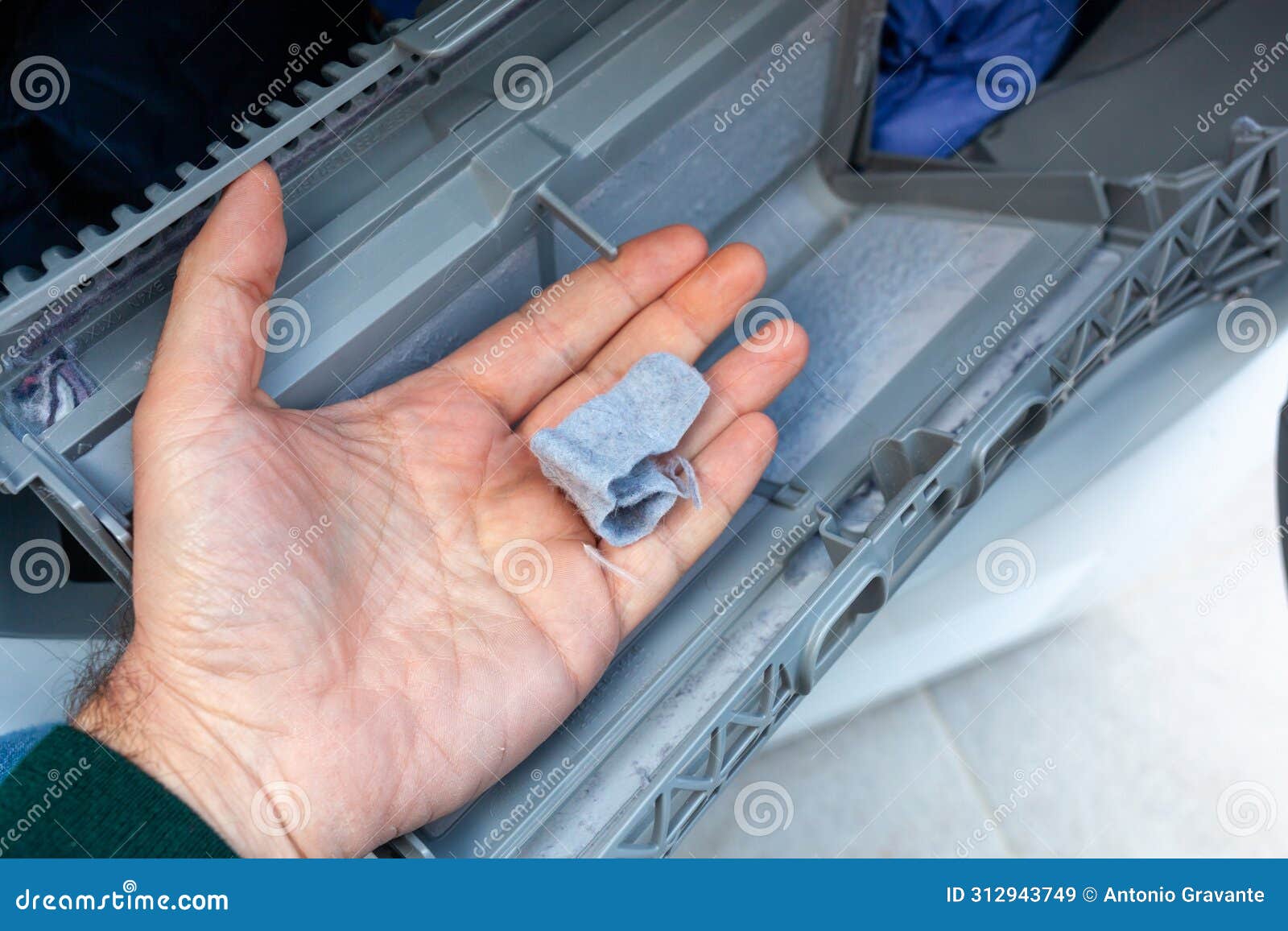 hand removing lint from a clothes dryer filter, home maintenance