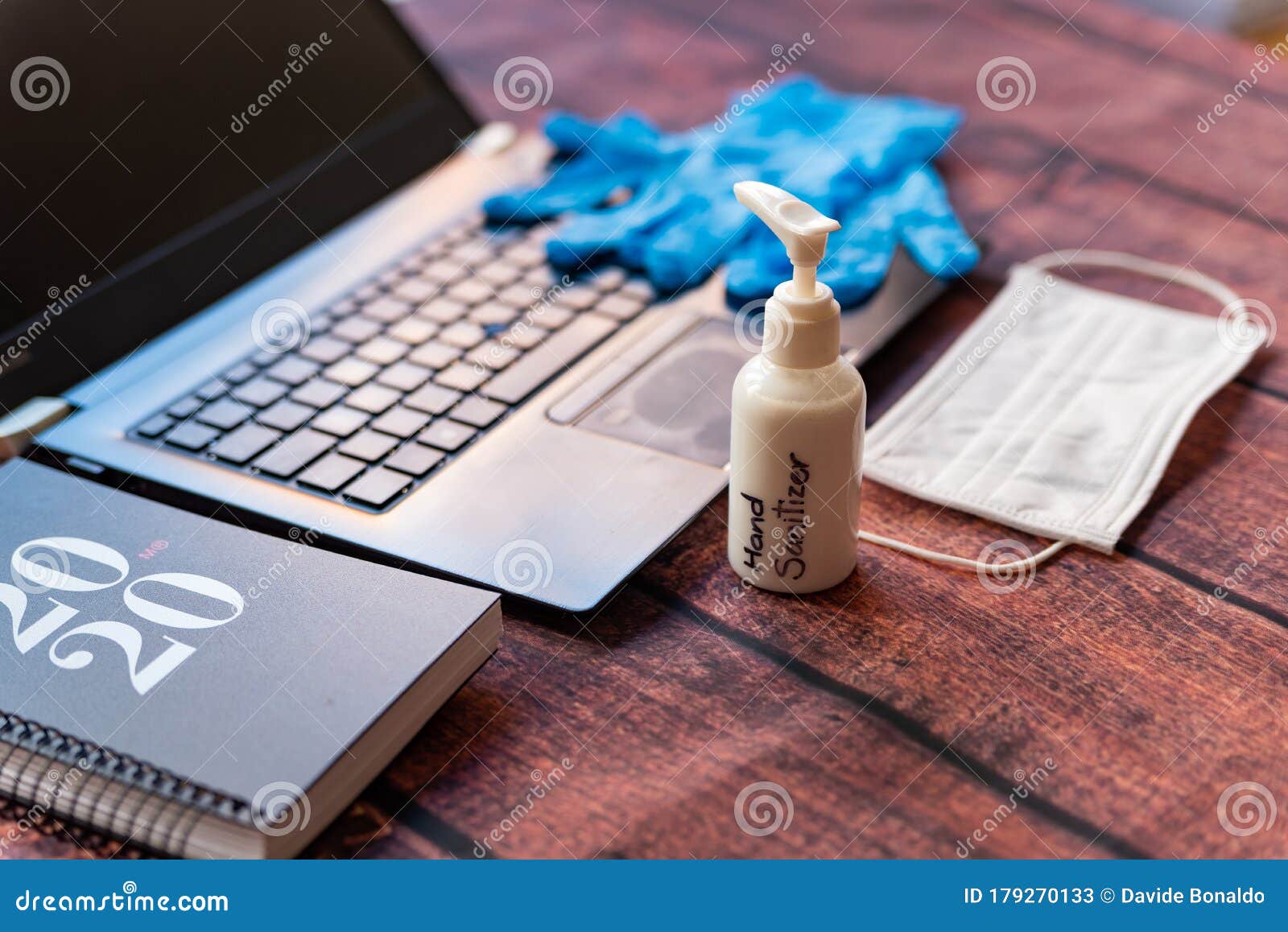 hand sanitizer work from home kit on wooden office desk with computer and face mask, a solution against the spread of corona virus