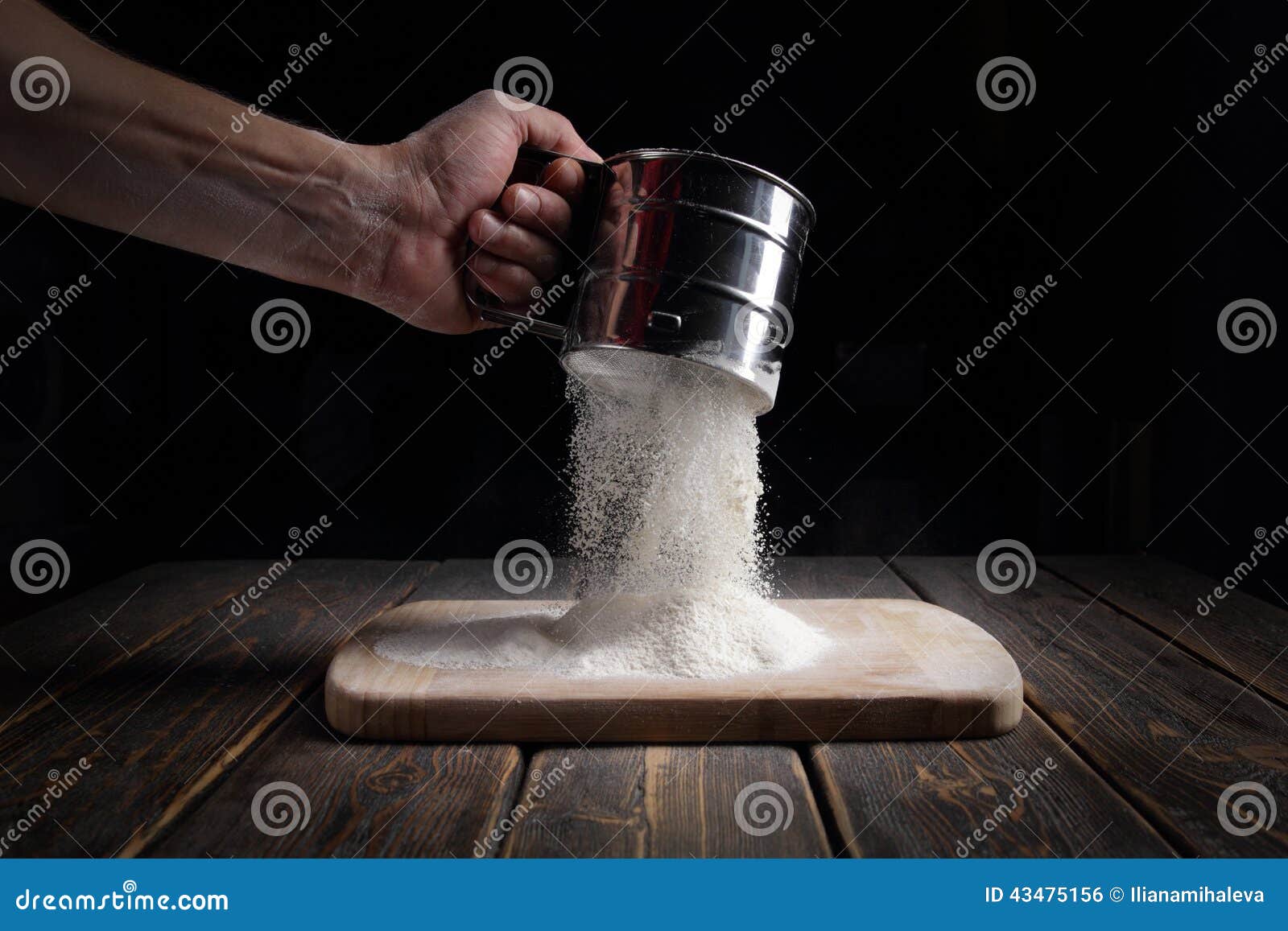 hand sifts the flour through a sieve.