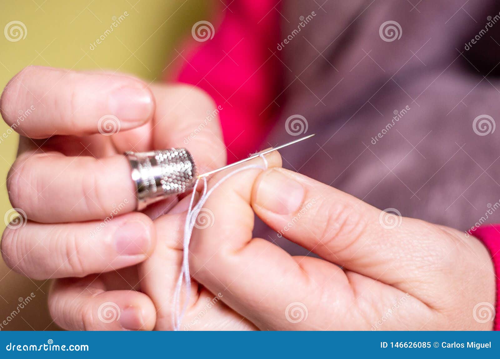 A Hand with Thimble Knotting and Cutting a Thread on a Needle in a