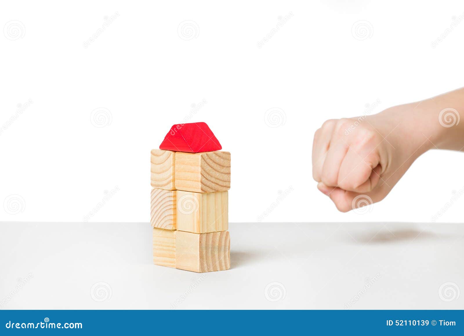 hand about to destroy house made of wooden blocks