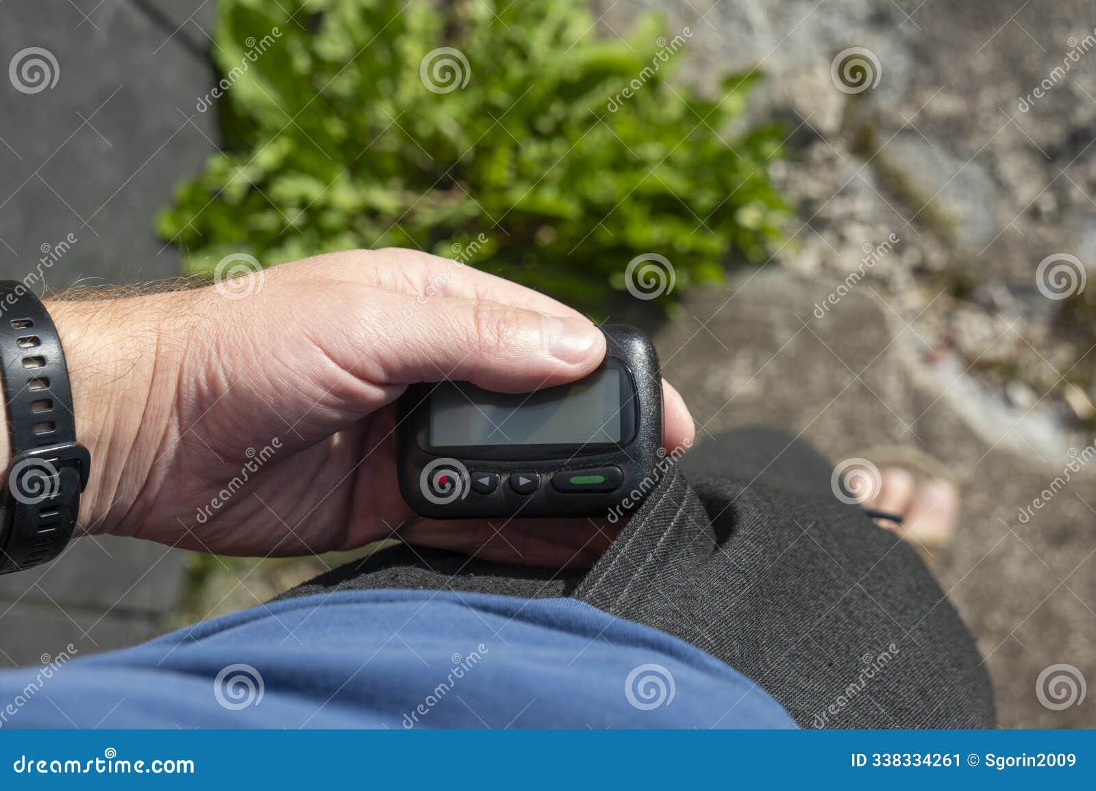 hand tooks out retro pager with a display from his pocket on the street
