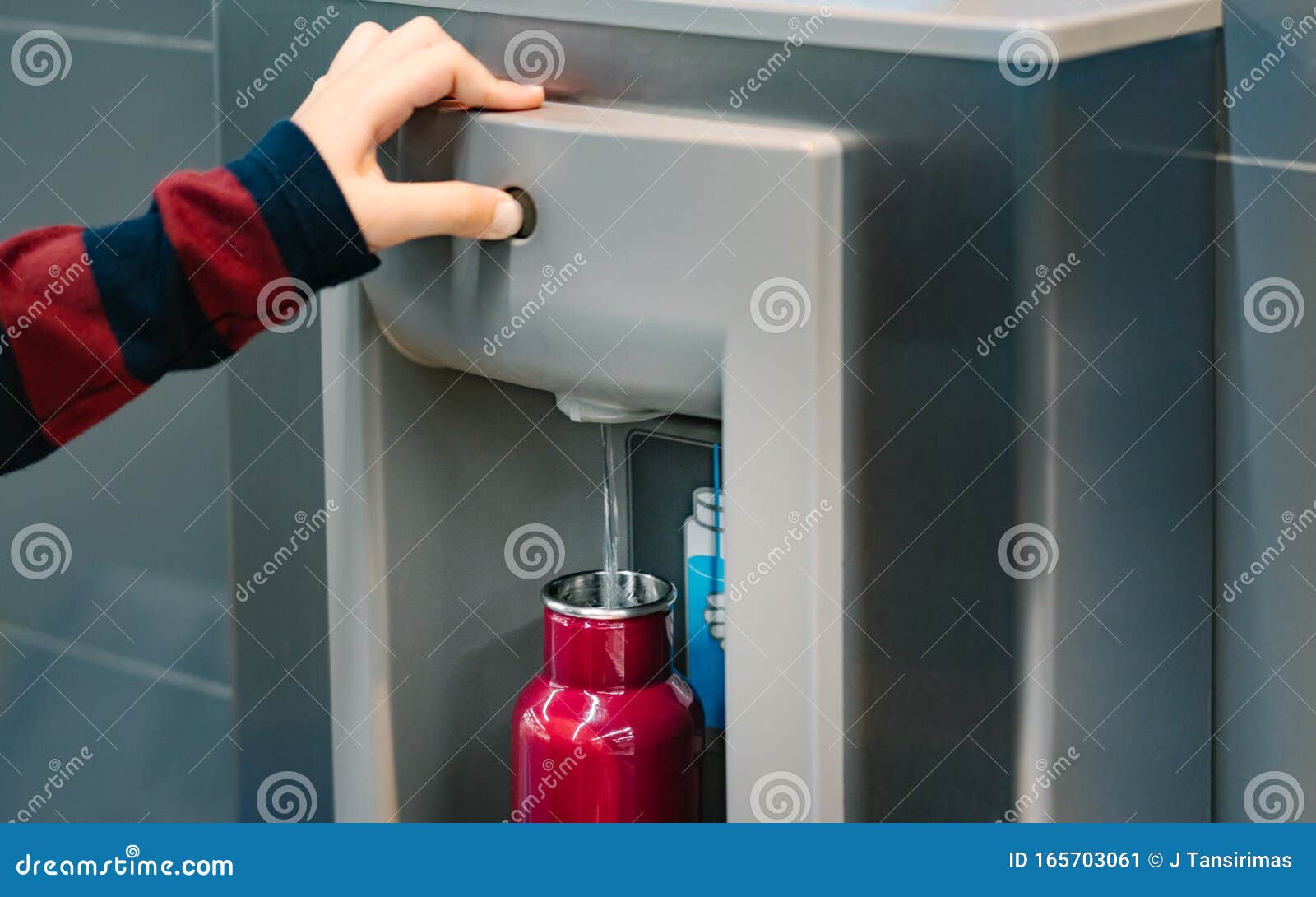 hand of a traveler pressed the button of drinking water filling station at the airport