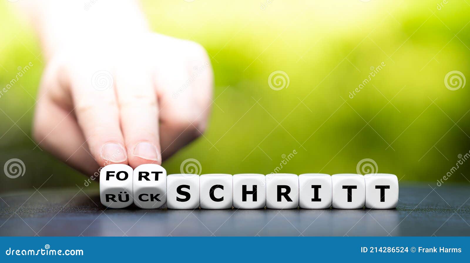hand turns dice and changes the german word `rÃÂ¼ckschritt` setback to `fortschritt` progress.