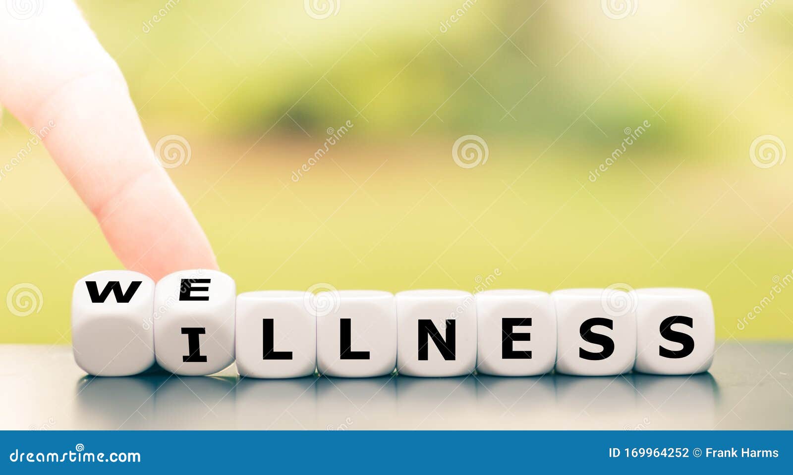 hand turns dice and changes the word `illness` to `wellness`.