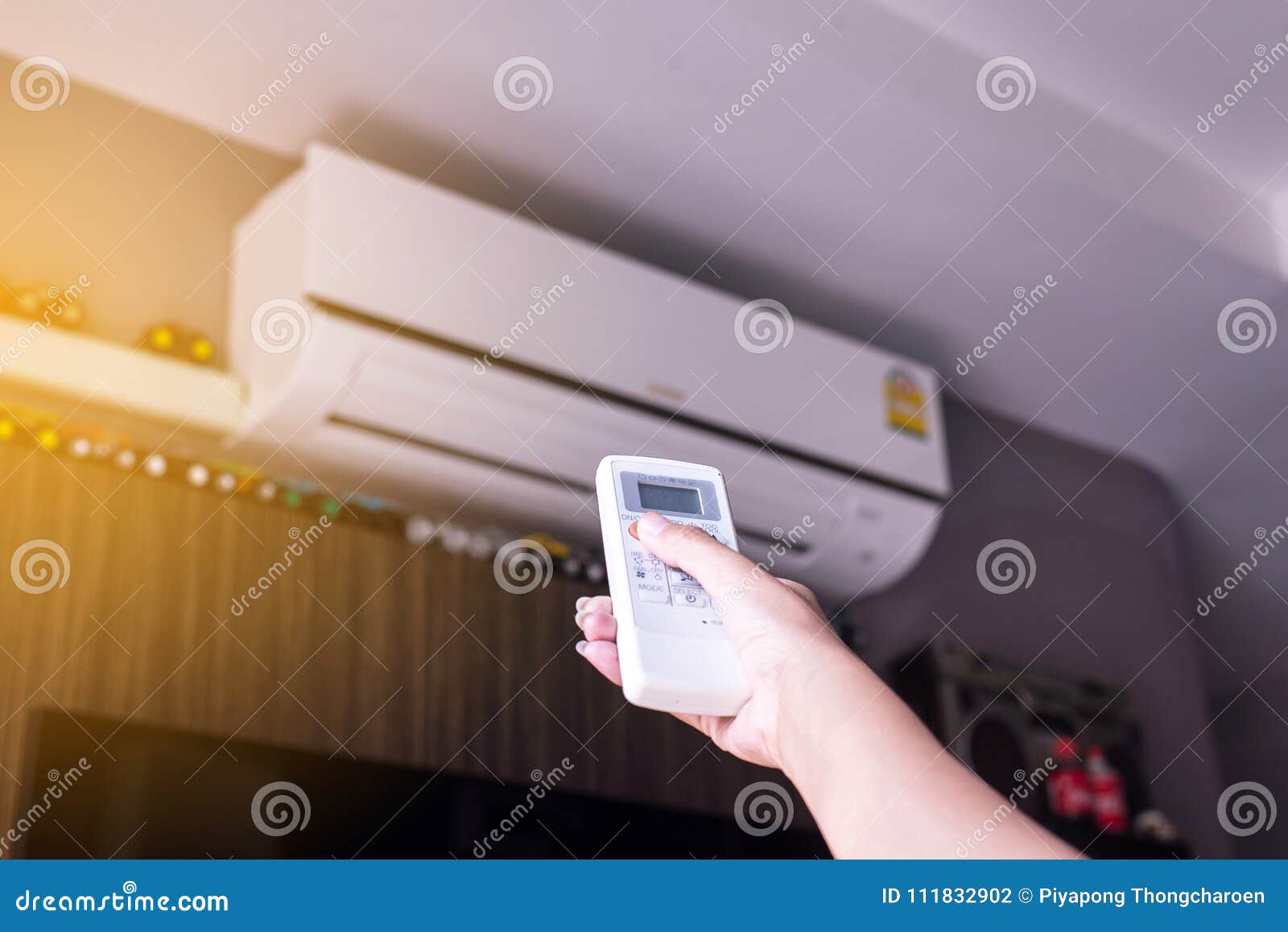 Hand Using a Remote Control To Activating Air Conditioning Stock Photo
