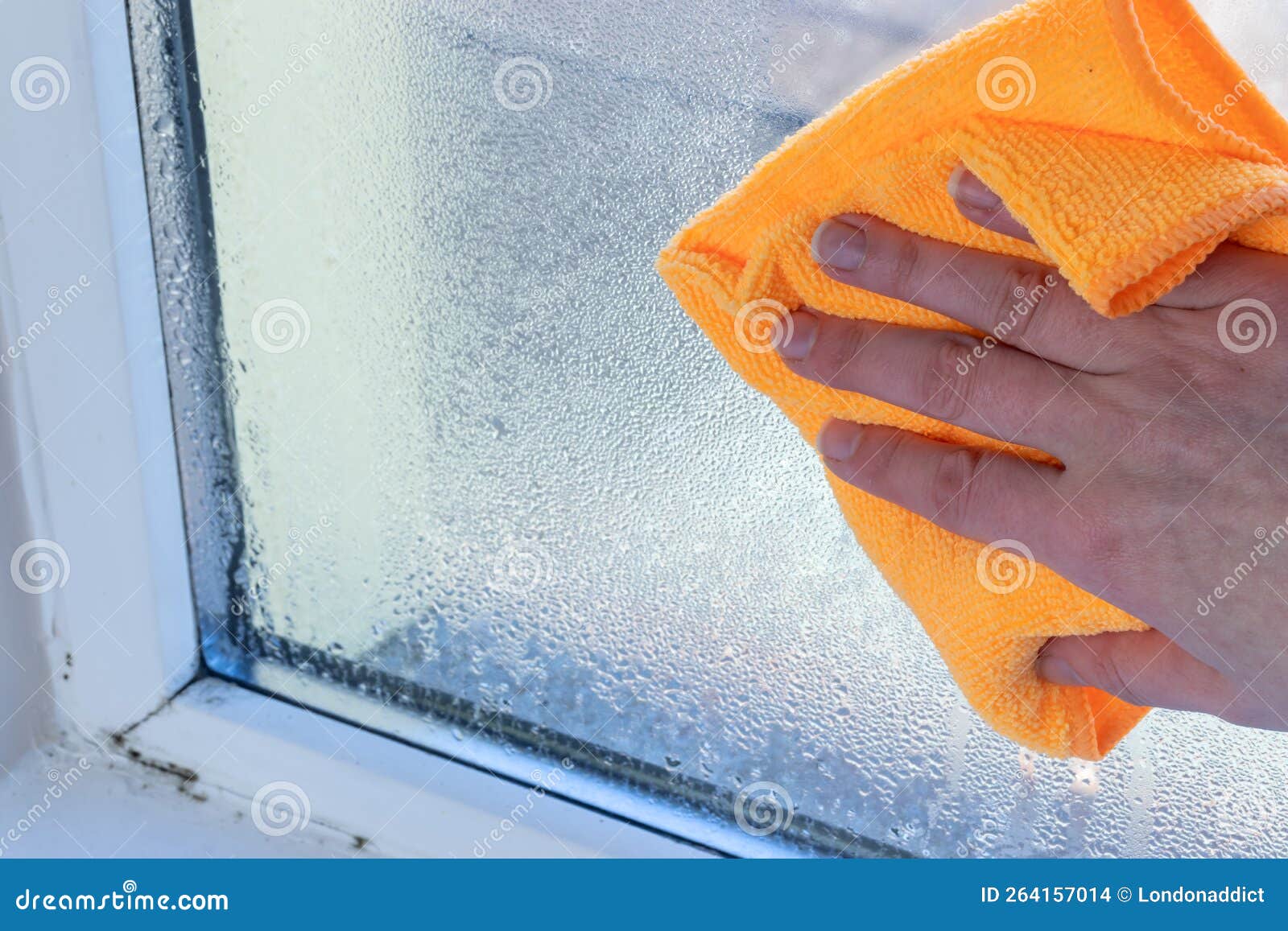 hand wipes off water condensation from plastic window glass in the room