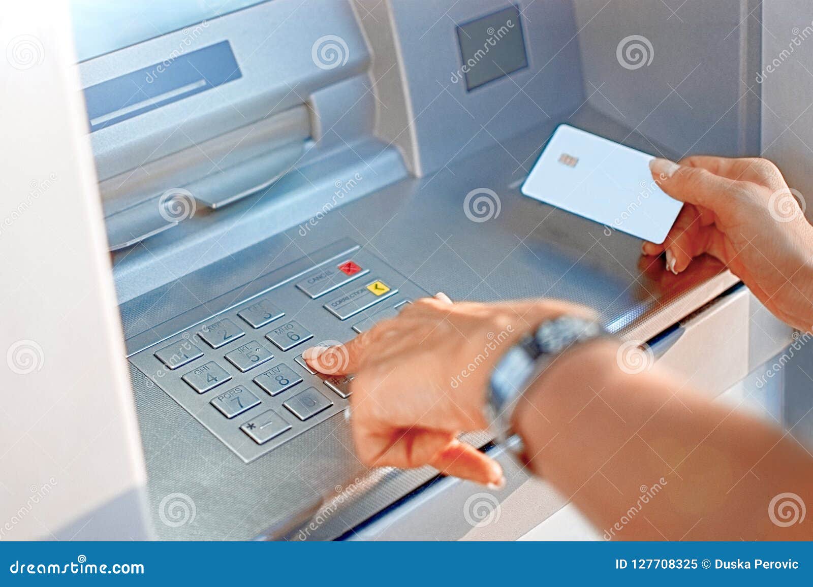 hand of a woman with a credit card, using an atm. woman using an atm machine with her credit card.