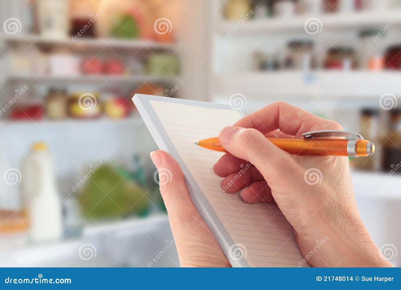 hand writing a list in front of an open fridge