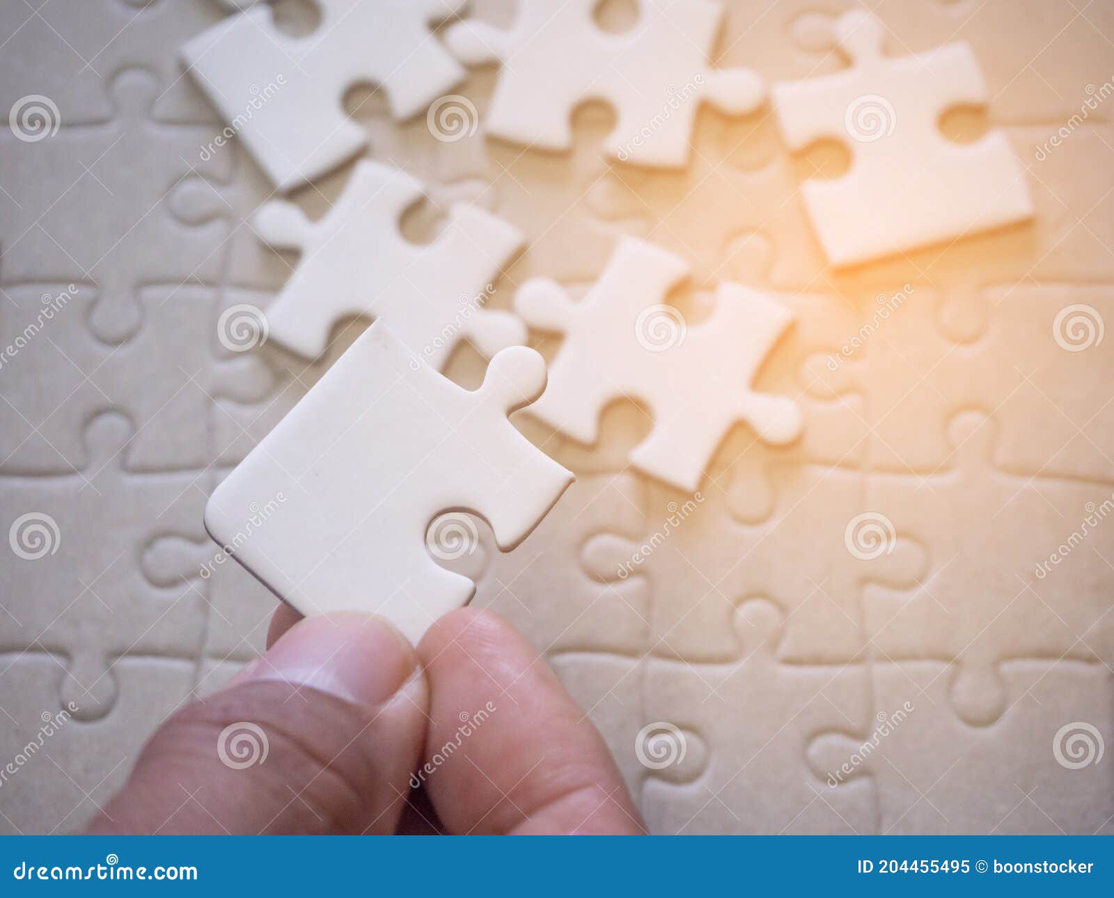 Hand of a Young Man Holding a Jigsaw Puzzle with Sunlight Effect Stock
