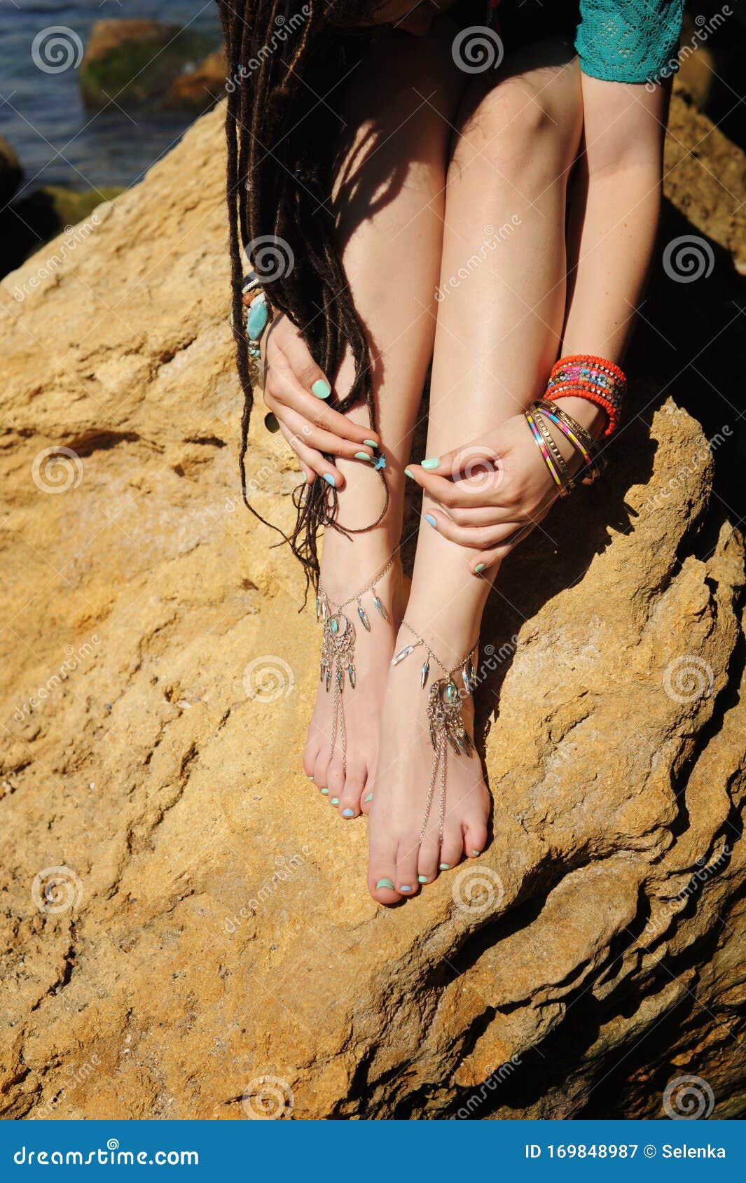 handcrafted bracelets on a woman legs, close up, white pedicure