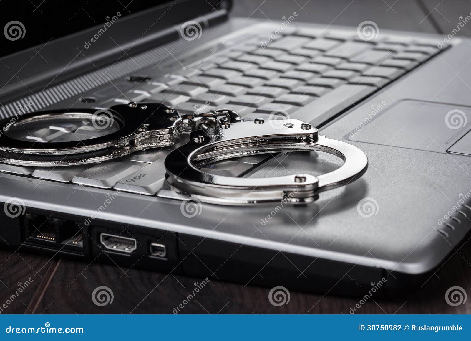 handcuffs on laptop cyber crime concept