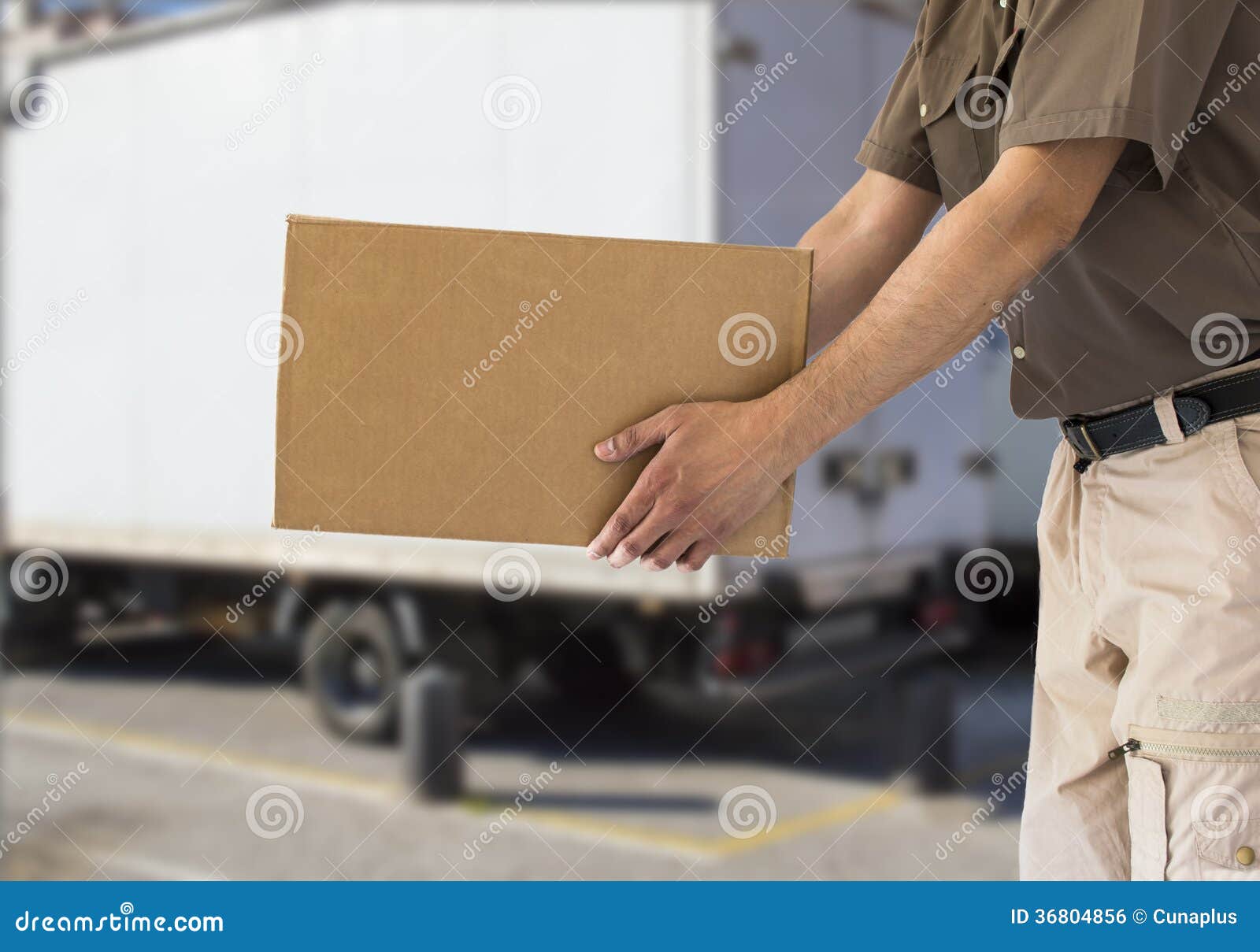 Man handing out cardboard box with a truck