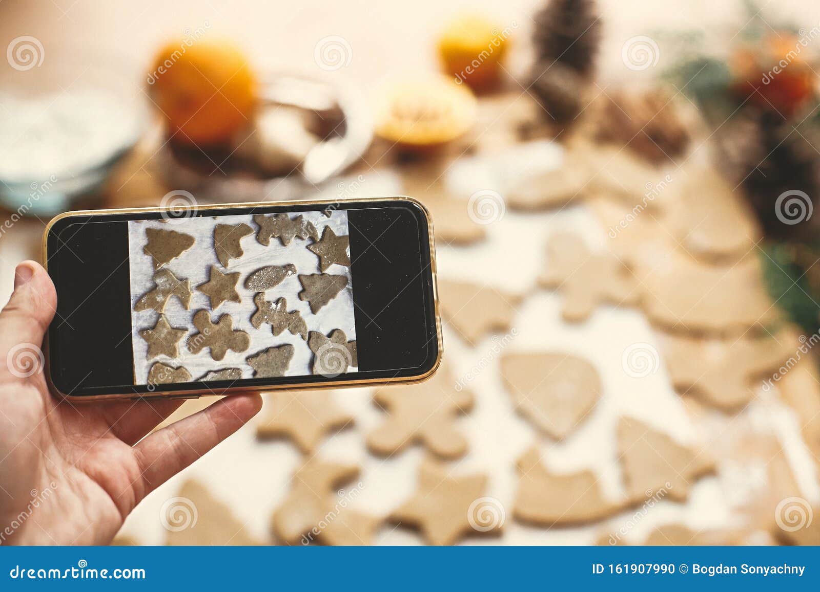 Handje Met De Telefoon En Foto's Van Het Proces Van Het Maken Van Kerstbroodkoekjes Nemen Op De Smartphone Van Raw Stock Foto - Image of kaneel, 161907990